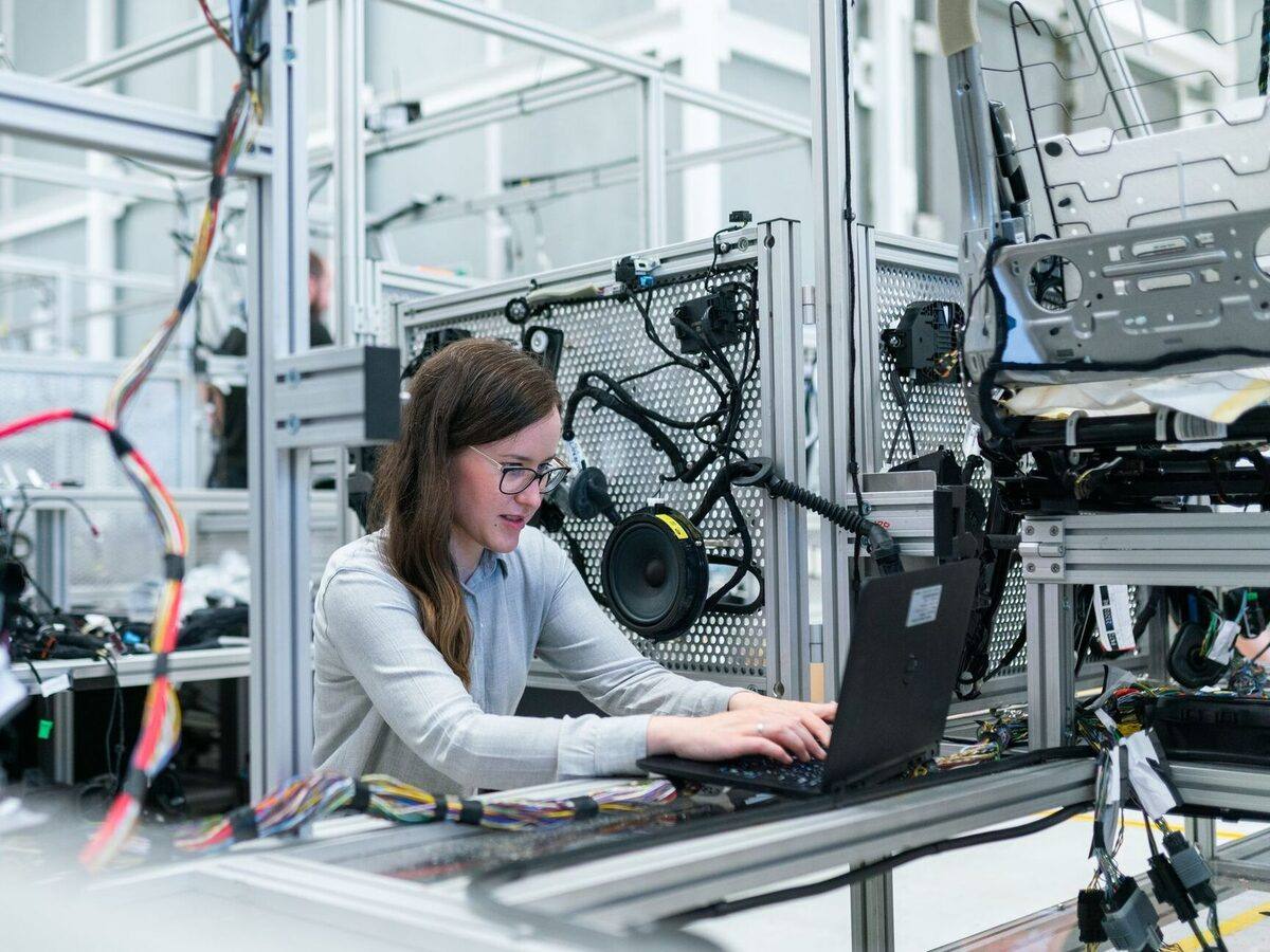 An engineer typing on a laptop at a test rig, surrounded by wiring looms and aluminium framing